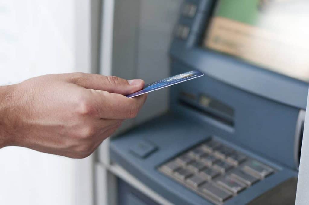 man inserting credit card into atm for cash advance